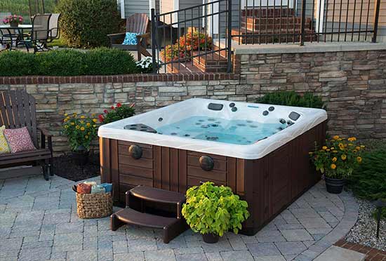 Hot tub installed on paver patio with landscaping